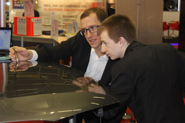 Dellenteam-Mitglied CAR-REP-Profiteam Denk auf einer Fachmesse, Peter Denk zeigt eine Delle auf der Motorhaube