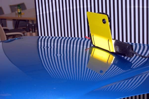 Dellenteam zeigt eine Lampe für Dellentechniker, die die Dellen sichtbar macht.