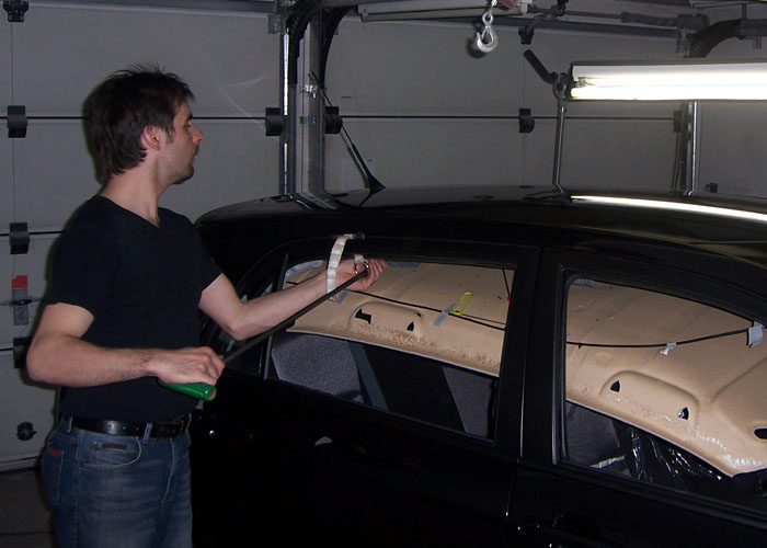 Dellenteam-Mitglied Andreas Schedl drückt eine Dellen auf einem Autodach